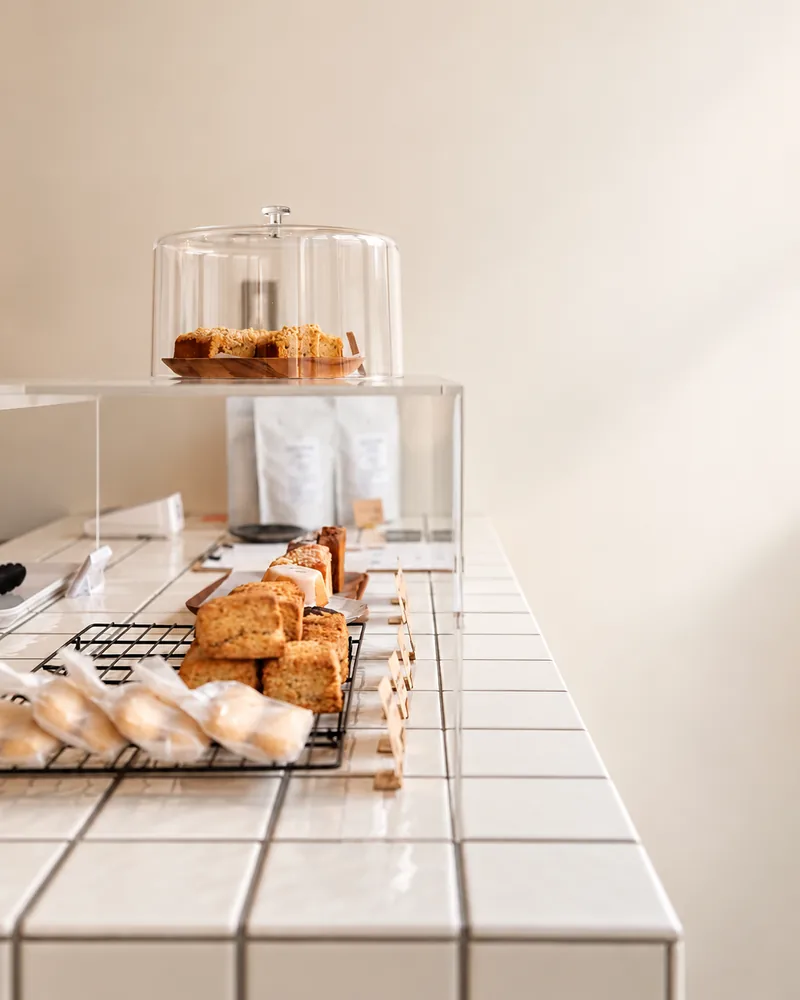 Rows of baked goods in the white tiled showcase, with more bakes under a glass dome at the back